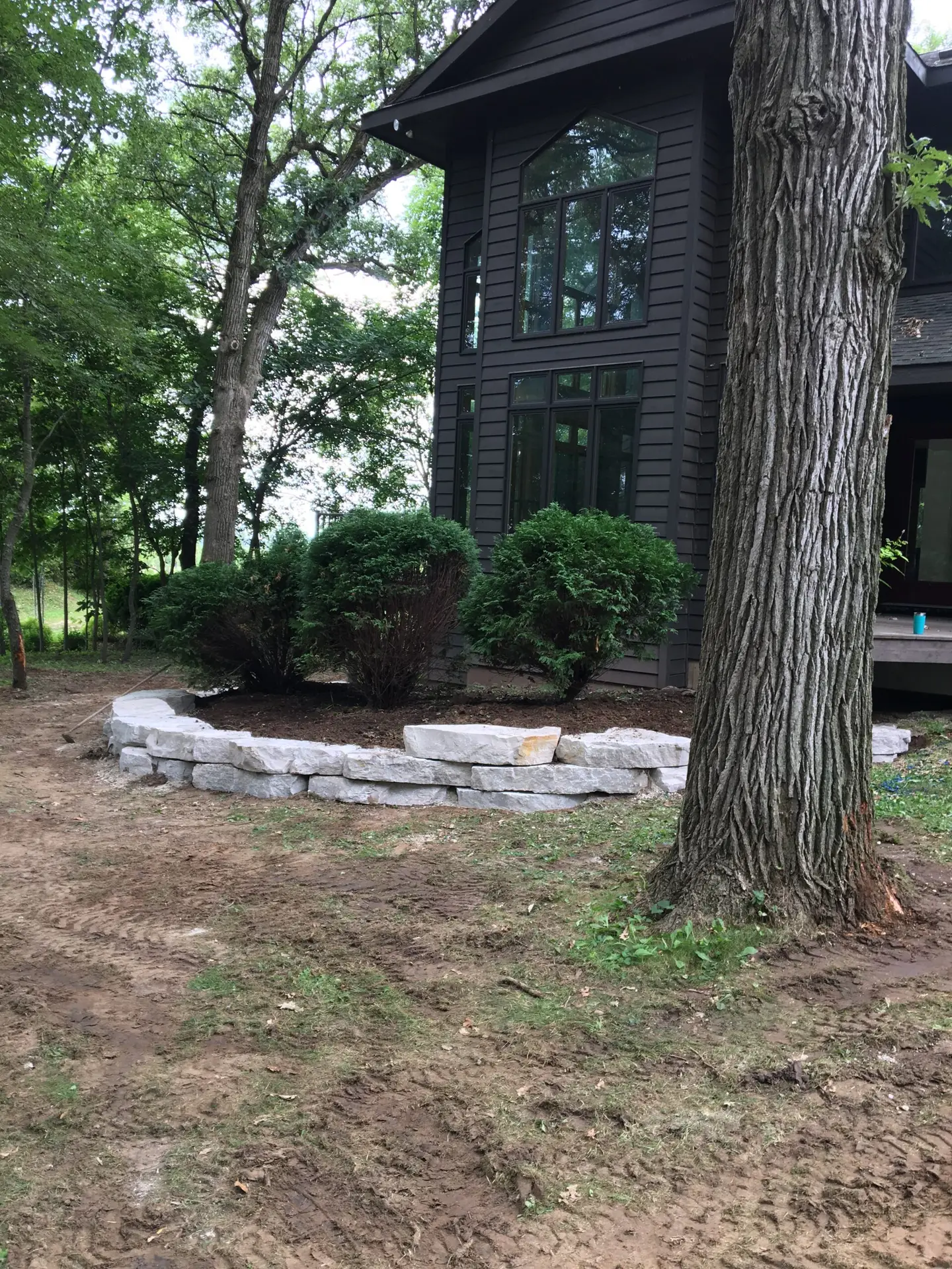 Limestone boulder retaining wall along wooded property