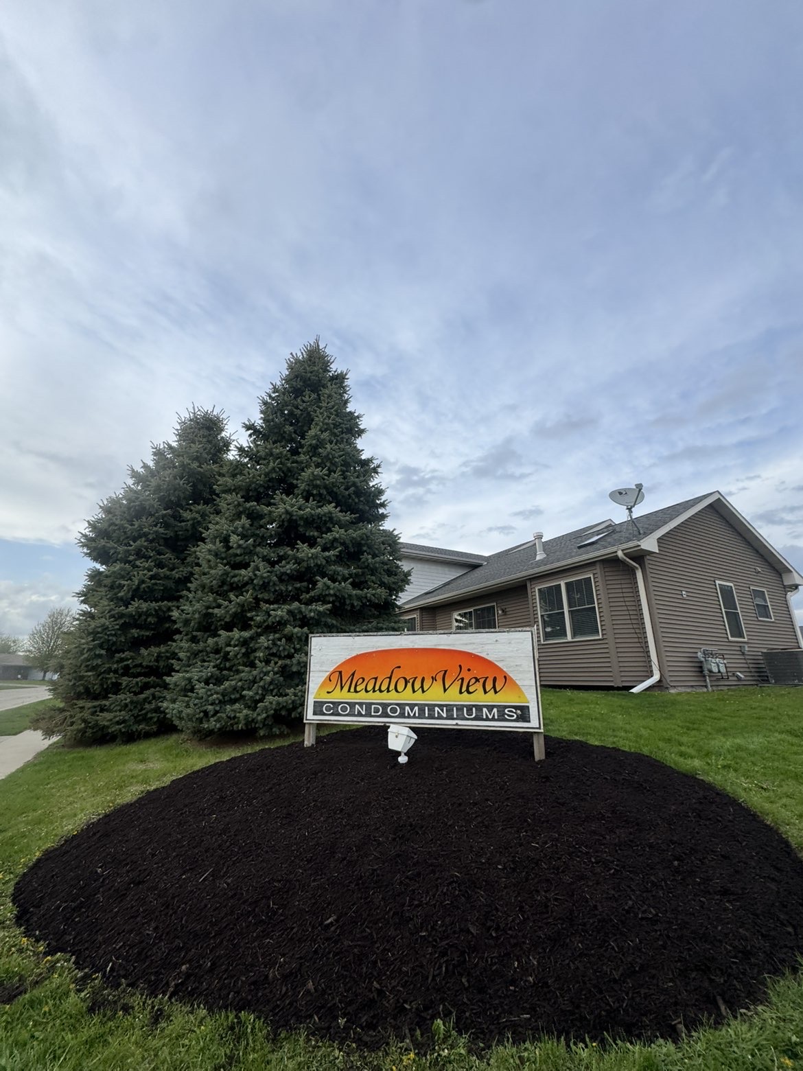 Newly installed landscape with layered garden beds and fresh mulch around a modern home